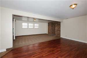 Carpeted empty room with brick wall, a wood stove, and a textured ceiling