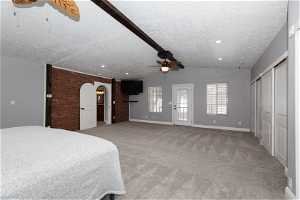 Unfurnished bedroom featuring light carpet, ceiling fan, a textured ceiling, and vaulted ceiling