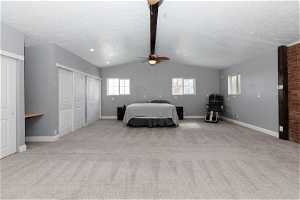 Unfurnished bedroom with lofted ceiling with beams, brick wall, ceiling fan, and light carpet