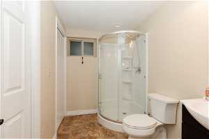 Bathroom with a textured ceiling, vanity, toilet, a shower with shower door, and tile floors