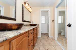 Bathroom with large vanity, tile floors, and toilet