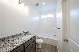 Full bathroom featuring hardwood / wood-style flooring, tub / shower combination, toilet, and vanity