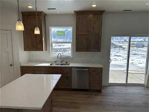 Kitchen with dishwasher, light stone counters, sink, dark hardwood / wood-style floors, and pendant lighting