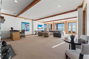 Carpeted living room with beamed ceiling, a water view, and french doors