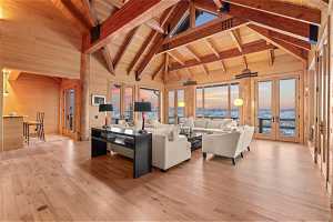 Living room with light hardwood / wood-style floors, wooden ceiling, beamed ceiling, french doors, and wooden walls