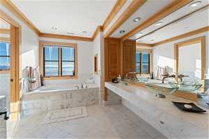 Bathroom featuring vanity, tiled tub, crown molding, and tile flooring
