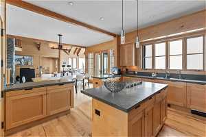 Kitchen featuring a kitchen island, light hardwood / wood-style floors, decorative light fixtures, and beamed ceiling