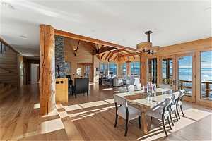 Dining space featuring light hardwood / wood-style flooring, lofted ceiling with beams, wooden walls, french doors, and a water view