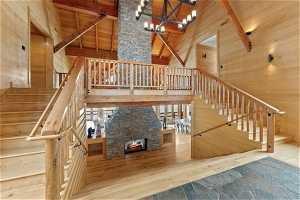 Staircase with a fireplace, beamed ceiling, a high ceiling, and light wood-type flooring