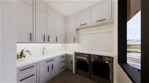 Laundry room with dark tile floors, separate washer and dryer, cabinets, and sink