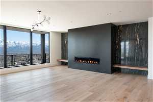 Empty room with a large fireplace, a mountain view, light hardwood / wood-style flooring, and a notable chandelier