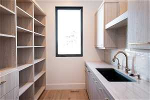 Kitchen with light brown cabinetry, sink, light hardwood / wood-style flooring, and tasteful backsplash