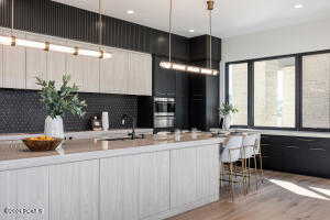 Kitchen featuring light hardwood / wood-style floors, stainless steel double oven, tasteful backsplash, and sink