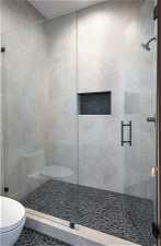 Bathroom featuring toilet, tile floors, and a shower with shower door