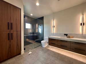 Bathroom with a shower with door, vanity, and toilet