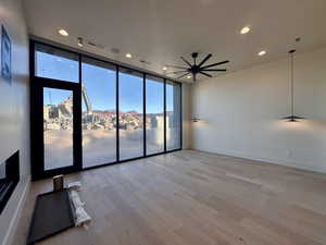 Spare room featuring light wood-type flooring, a wall of windows, and ceiling fan