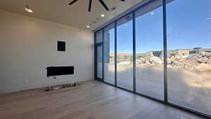 Unfurnished living room featuring hardwood / wood-style floors, a wall of windows, and ceiling fan