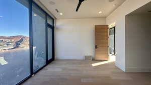 Spare room featuring a mountain view, hardwood / wood-style flooring, floor to ceiling windows, and ceiling fan