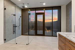 Bathroom with a shower with door, vanity, and a wall of windows