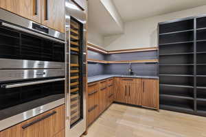 Kitchen featuring tasteful backsplash, sink, double oven, and light hardwood / wood-style floors