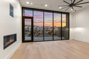 Empty room with expansive windows, ceiling fan, and light hardwood / wood-style flooring