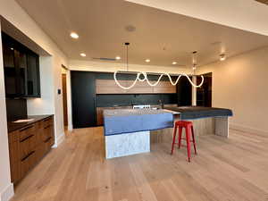 Kitchen with a kitchen breakfast bar, pendant lighting, and light hardwood / wood-style floors