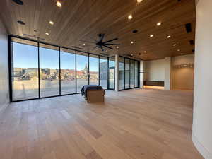 Spare room with ceiling fan, expansive windows, wooden ceiling, and light hardwood / wood-style floors