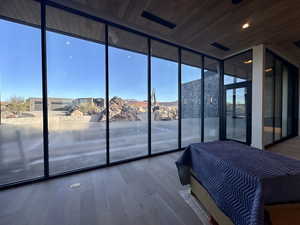 Unfurnished bedroom featuring a mountain view, hardwood / wood-style flooring, expansive windows, and wood ceiling