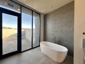 Bathroom with a bath, a wall of windows, and tile walls