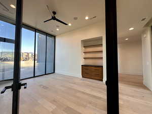 Empty room with floor to ceiling windows, ceiling fan, and light hardwood / wood-style floors