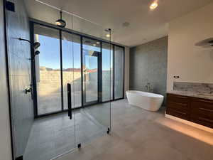 Bathroom featuring plus walk in shower, vanity, and a wall of windows