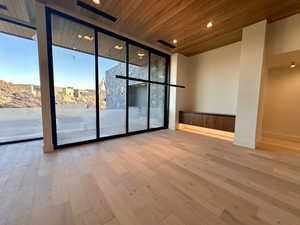 Spare room with light hardwood / wood-style flooring, wood ceiling, and a wall of windows