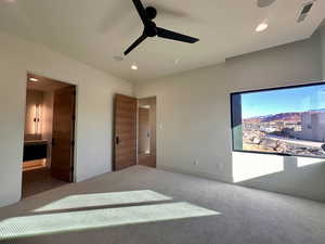 Unfurnished bedroom featuring ceiling fan, carpet floors, and ensuite bath