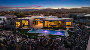 Back house at dusk featuring a mountain view and a patio