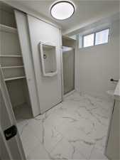 Bathroom featuring a shower with shower door, vanity, tile flooring, and toilet