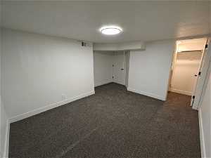 Unfurnished bedroom featuring a closet, dark colored carpet, a textured ceiling, and a walk in closet
