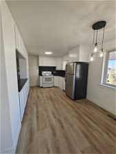 Kitchen featuring light hardwood / wood-style flooring, stainless steel fridge, white electric range, and white cabinets