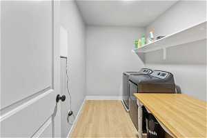 Laundry area with light hardwood / wood-style flooring and washing machine and dryer