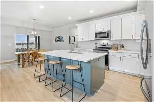 Kitchen with tasteful backsplash, a breakfast bar area, appliances with stainless steel finishes, and a kitchen island with sink