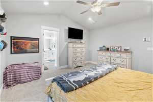Bedroom featuring ensuite bathroom, ceiling fan, light colored carpet, and lofted ceiling