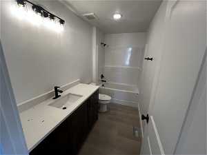 Full bathroom featuring shower / bath combination, vanity, a textured ceiling, toilet, and wood-type flooring