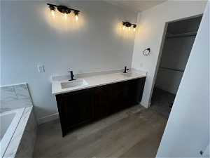 Bathroom featuring wood-type flooring, dual bowl vanity, and a bathing tub