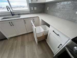 Kitchen featuring light wood-type flooring, backsplash, and white cabinets