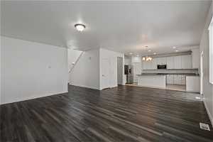 Unfurnished living room with dark hardwood / wood-style floors, sink, and a notable chandelier