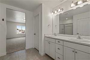 Bathroom with large vanity, dual sinks, tile floors, and a textured ceiling