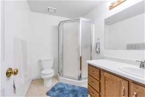 Bathroom featuring vanity, toilet, walk in shower, and tile flooring