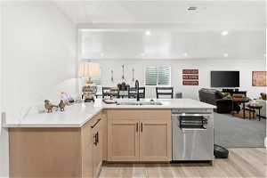 Kitchen with stainless steel dishwasher, light hardwood / wood-style flooring, light brown cabinets, and sink