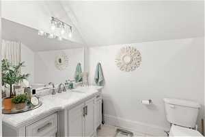 Full Bathroom with vaulted ceiling, tile floors, vanity, and toilet