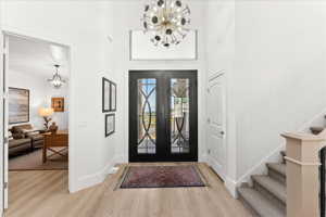 Foyer entrance with a chandelier, light wood-type flooring, and french doors