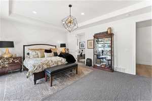 Primary Bedroom with an inviting chandelier, hardwood / wood-style floors, and a tray ceiling